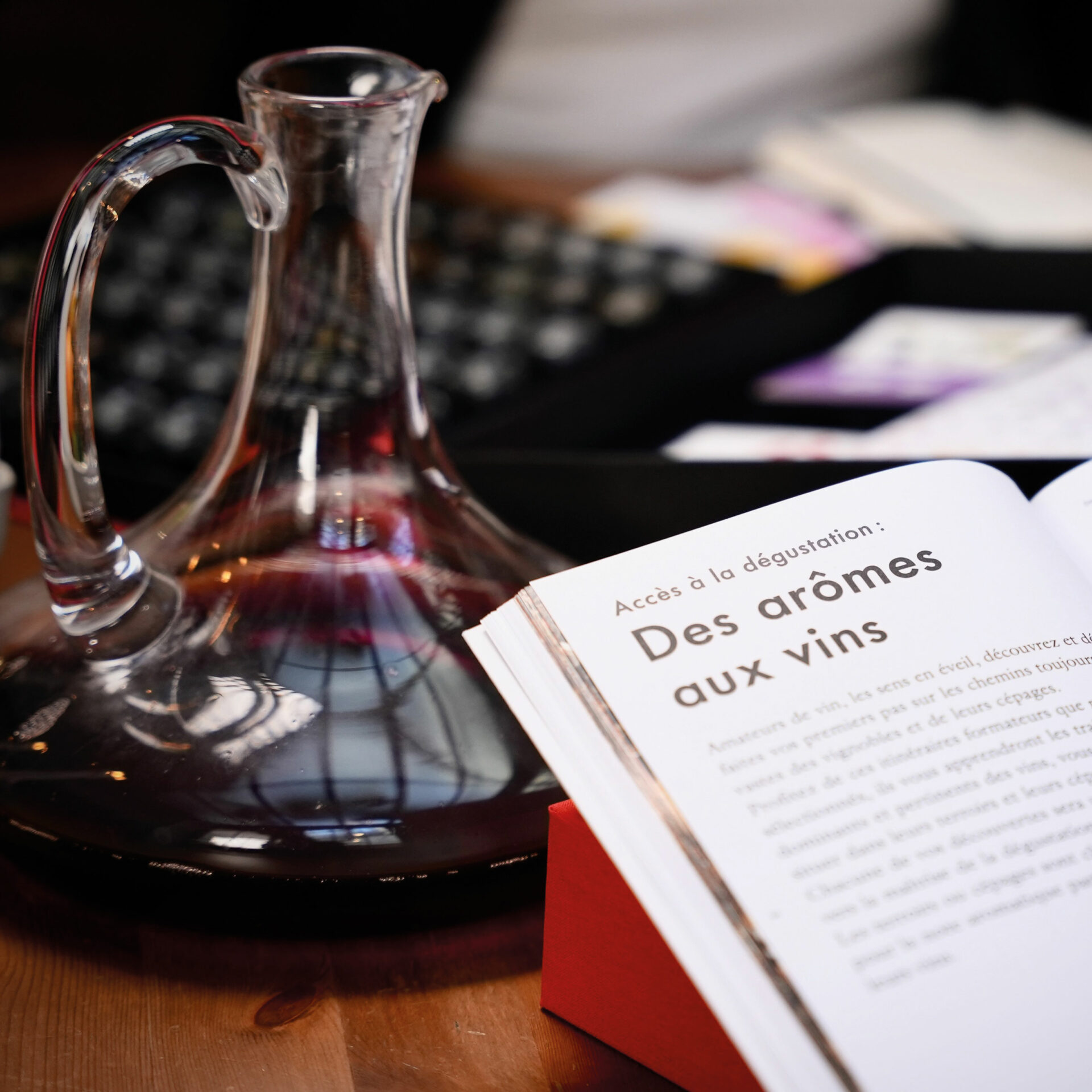 Personne qui lit un livre à tablé, avec une carafe de vin rouge